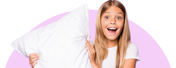 Uśmiechnięta nastolatka wskazuje z poduszką w rękach